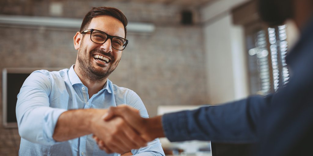 a person smiling while doing handshake