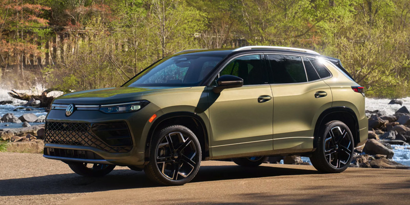 Green Volkswagen SUV parked near a scenic river landscape.
